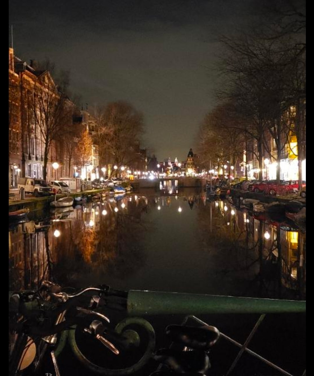 The same canals after dark, lights doubled on the water